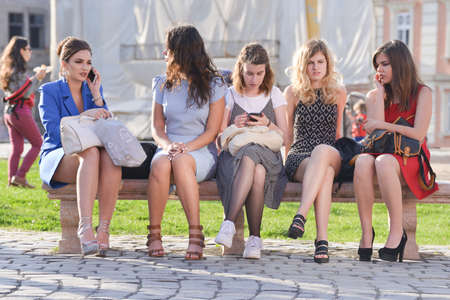 TIMISOARA, ROMANIA - April 24, 2018: beautiful young girls are talking while sitting on a bench on...
