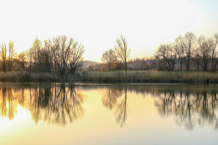 Autumn trees display golden and red hues along the lake, mirrored beautifully in calm reflective...