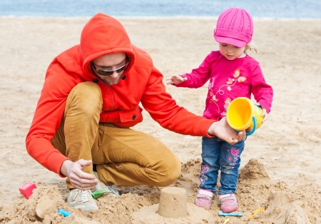 Dad and daughter playing on the beach in the sandの写真素材
