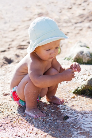 cute baby playing on the beach with waterの写真素材