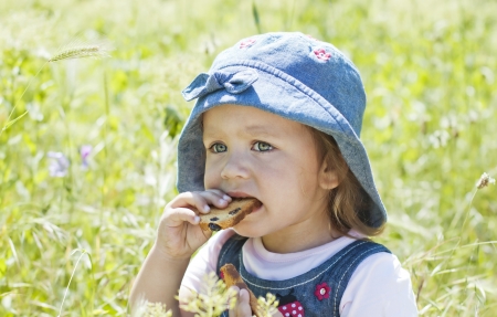 Cute baby  eating crackers on green grass outdoors in spring parkの写真素材