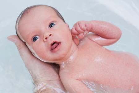 bathing baby in the bath father handsの写真素材