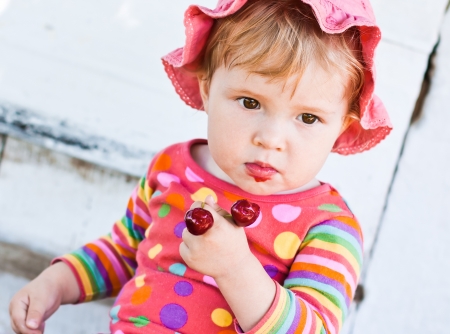 cute baby eats cherries outdoorsの写真素材