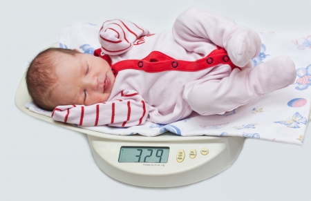cute baby on the scales on a white backgroundの写真素材