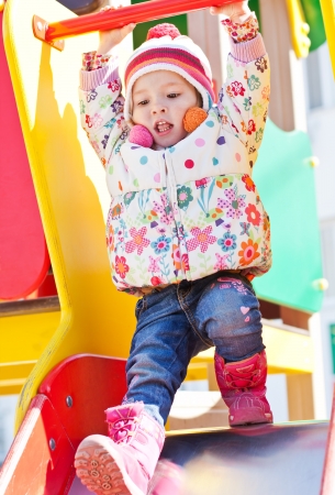 cheerful little girl playing on the playground on a sunny dayの写真素材