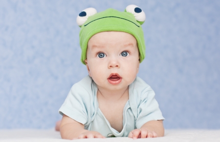 baby in the hat frog lying on his stomachの写真素材