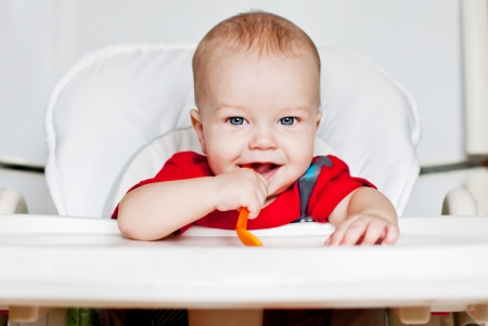 laughing boy holding a spoon on a white backgroundの写真素材