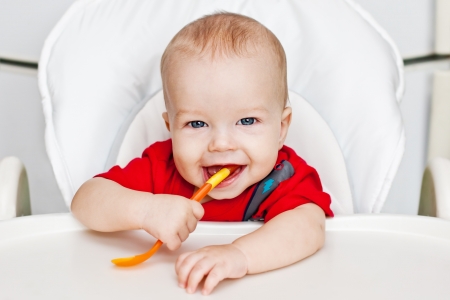 laughing boy holding a spoon on a white backgroundの写真素材