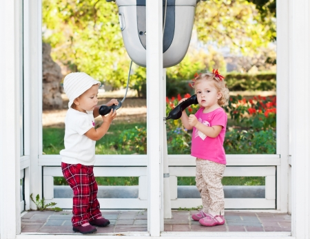 toddler girls talking by the city phones (not a traidmark)の写真素材