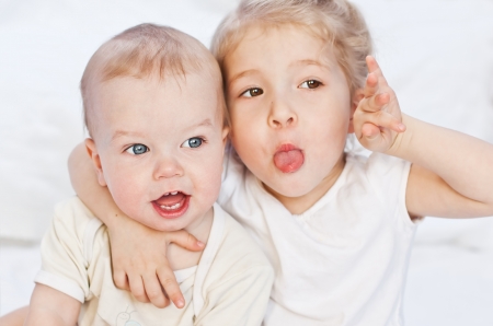 adorable happy little boy dabbles with her older sister on a white backgroundの写真素材