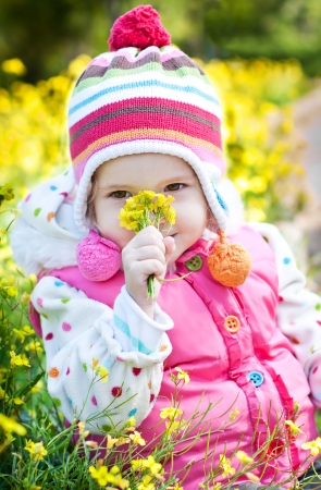 happy little girl holding a bouquet of yellow flowers on a walkの写真素材