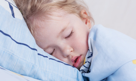 toddler girl is sleeping covered with a blanketの写真素材