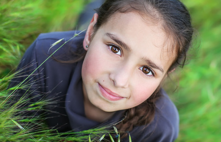 portrait of pretty  girl with brown eyes  spring or summer on a sunny day lying on the grassの写真素材