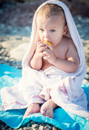 cute baby on the sea eating apricotの写真素材
