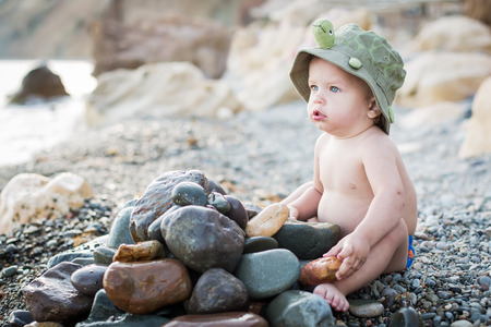 cute toddler on the beach playing with stonesの写真素材
