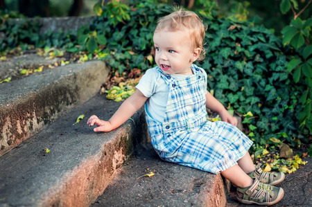cute toddler boy sitting on the stairs in the parkの写真素材