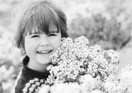 funny happy little girl holding a bouquet of standing on a meadow ( black and white )の写真素材