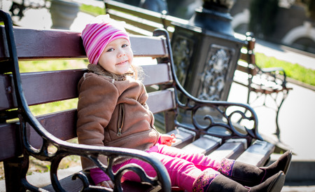 toddler girl sitting on the bench outdoorの写真素材