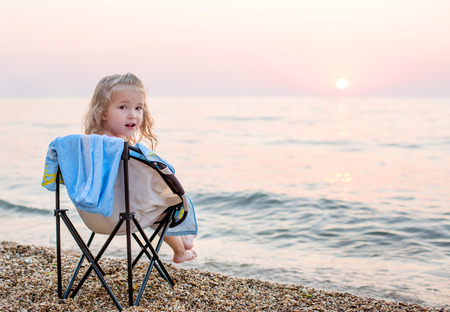 happy little girl on the beach sitting on a chairの写真素材