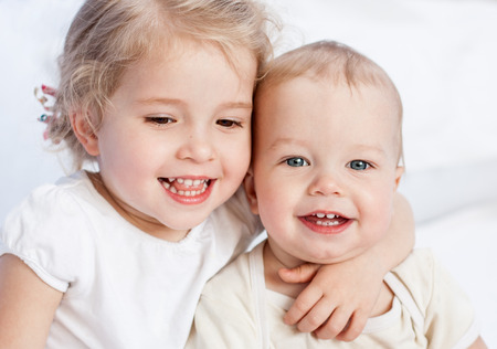 happy little sister hugging her brother on a white backgroundの写真素材