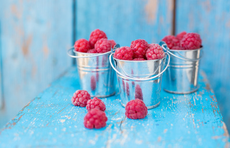 ripe raspberry in a pail on a wooden tableの写真素材
