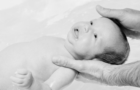 bathing baby in the bath father hands ( black and white )