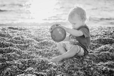 cute toddler boy playing on the beach at sunset ( black and white )の写真素材