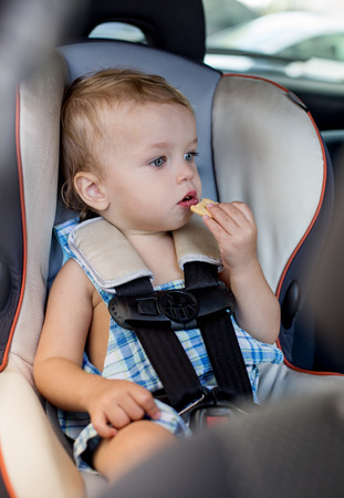 Happy Toddler boy in the car eating cookiesの写真素材
