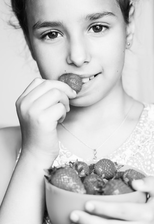 child eating a strawberry on white background  ( black and white )の写真素材