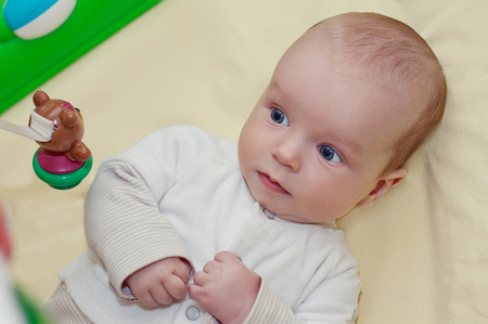 cute newborn looks at toys lying on his backの写真素材