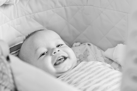 Cute  baby smiling looking at the camera lying in the cradle  ( black and white )の写真素材