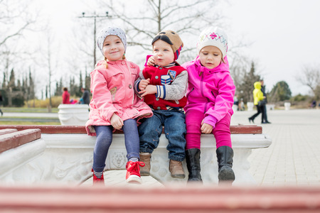 fun toddlers playing in the park sitting on the benchの写真素材