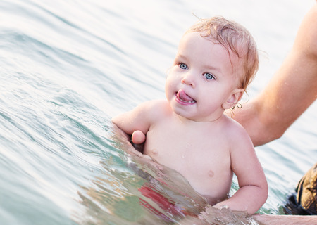 Toddler boy having fun in the hands of the father swims summerの写真素材