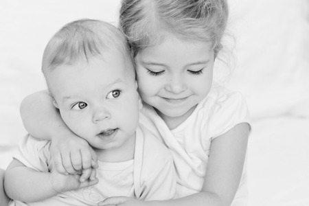 happy little sister hugging her brother on a white background ( black and white )の写真素材
