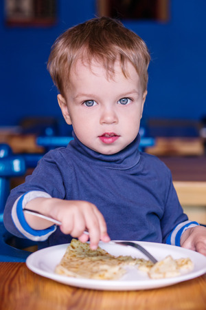 Toddler boy in a cafe eating a pancakeの写真素材