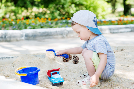 Toddler boy playing in the sand in the summerの写真素材