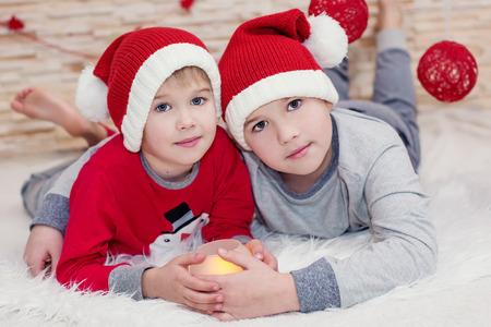 two little child santa embracing hold a candleの写真素材