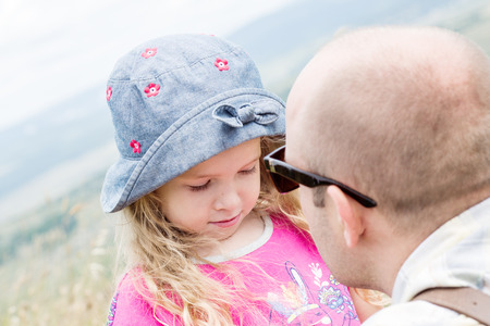 Dad kissing and soothes daughter outdoorsの写真素材