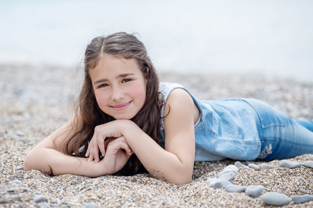 Happy little girl lying on the beach dressedの写真素材