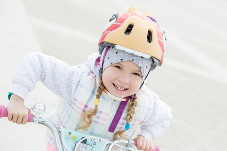happy little girl in a helmet on a bicycle on a white backgroundの写真素材