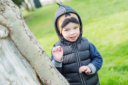happy little child peeking from behind a treeの写真素材