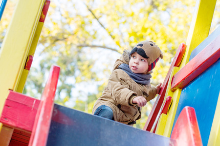 Curious Toddler boy climbing on  playground outdoorsの写真素材