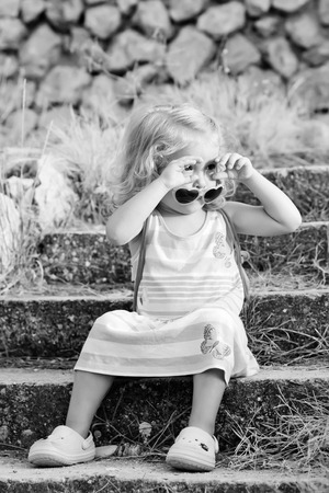 Toddler cute little girl in glasses at sunset ( black and white )の写真素材