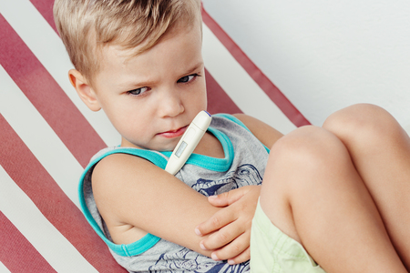 Little boy measures the temperature in the summerの写真素材