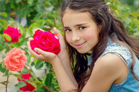 Portrait of brown-eyed little girl with a red roseの写真素材