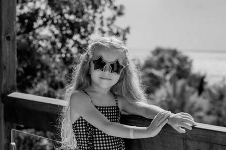 Cute little girl is having fun on a terrace near the sea beach (black and white)の写真素材