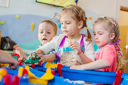 Three little kids play with water and toysの写真素材