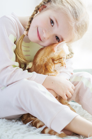 cute little girl holding a kitten on a ginger hand on a white backgroundの写真素材
