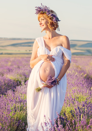 beautiful pregnant young woman in a white dress in lavender fieldの写真素材