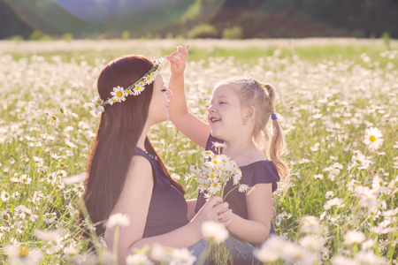 Mother with cute little child girl in the chamomile field in springの写真素材